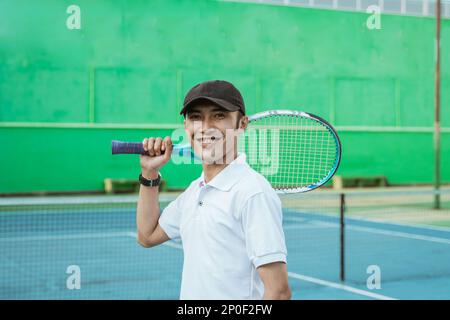 Atleta asiatico sorridente con racchetta Foto Stock