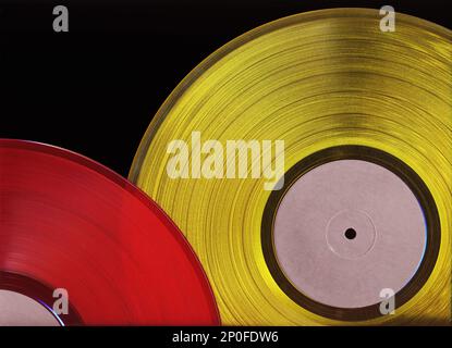 Due Vinile colorato record isolati su sfondo nero. Retrò dischi di musica di colori rossi e gialli di close-up Foto Stock