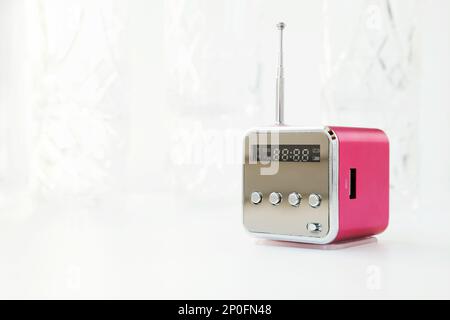 Carino moderna piccola radio con antenna su uno sfondo bianco. Nuovo cubo rosa ricevitore radio con copia spazio. Accesso wireless hi-tech electronic mass media equi Foto Stock