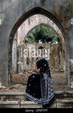 Una donna che si trova di fronte a una chiesa distrutta e straricciata sull'isola di Ross, precedentemente conosciuta come la Parigi dell'Oceano Indiano, Andamane, Andamane e Nicobar Foto Stock