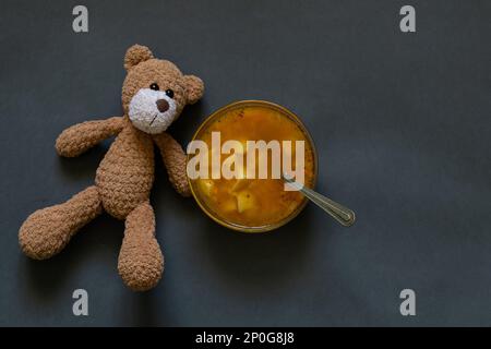 orsacchiotto e un piatto di zuppa accanto ad un buio Foto Stock