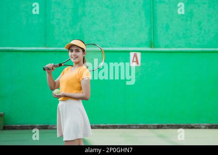 sorridente giocatore di tennis che porta racchetta e palla Foto Stock