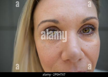 Primo piano testa tagliata ripresa di una donna bionda con messa a fuoco per i suoi occhi Foto Stock