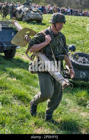 Reenactor in uniforme tedesca Waffen-SS, recante un mortaio, alla rievocazione della battaglia del WW2, Jelenia Gora, bassa Slesia, Polonia Foto Stock
