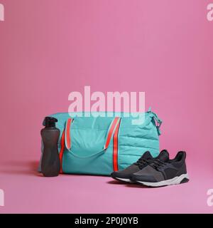 Borsa da palestra blu e accessori sportivi su sfondo rosa Foto Stock