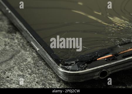 Smartphone con schermo incrinato su sfondo di pietra grigia, primo piano. Riparazione del dispositivo Foto Stock