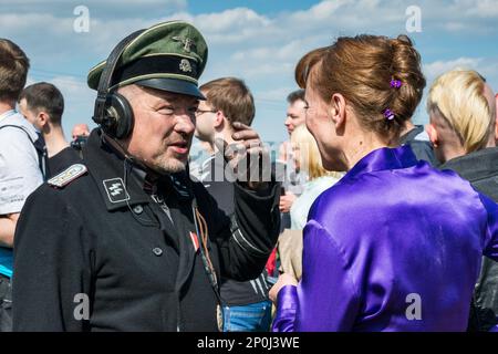 Reenactor in uniforme tedesca Waffen-SS, pilota carro armato, spettatore donna, parlando dopo la rievocazione della battaglia WW2, Jelenia Gora, bassa Slesia, Polonia Foto Stock