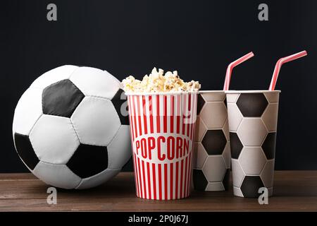 Palla di calcio con popcorn e tazze su tavolo di legno Foto Stock