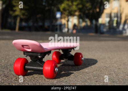 Skateboard rosa con ruote rosse su asfalto all'aperto Foto Stock