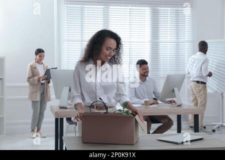 Nuovo collega che disimballa la scatola con gli articoli personali sul posto di lavoro in ufficio Foto Stock