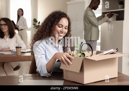 Nuovo collega che disimballa la scatola con gli articoli personali sul posto di lavoro in ufficio Foto Stock