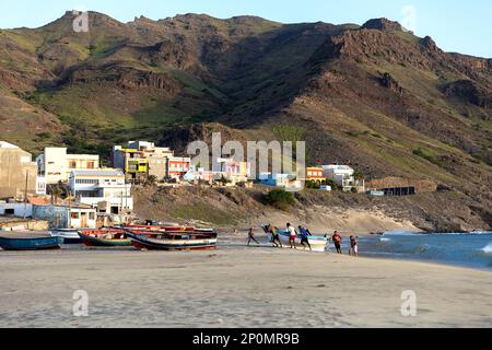 Pescatori locali che tirano a terra una tradizionale barca da pesca in un villaggio di pescatori di Sao Pedro sull'isola di Sao Vicente a Cabo verde, in Africa Foto Stock