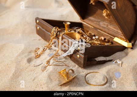 Aprire il petto di legno con tesori sulla sabbia Foto Stock