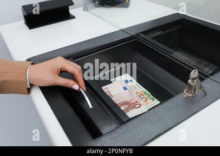 Cassiere con denaro in banca, primo piano. Cambio valuta Foto Stock