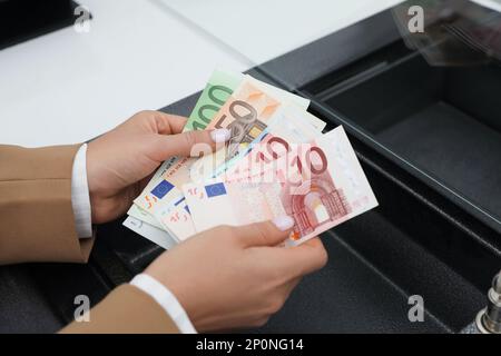 Donna con soldi alla finestra del reparto di cassa, primo piano. Cambio valuta Foto Stock