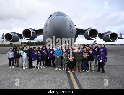 Studenti e insegnanti della Stafford Elementary School, Tacoma, posa per una foto di gruppo di fronte a un C-17 Globemaster III assegnato alla 62d Airlift Wing durante un evento Aviation Inspiration and Mentorship (AIM) alla base congiunta Lewis-McChord, Washington, 17 gennaio 2023. AIM è un programma di sensibilizzazione della comunità progettato per informare, influenzare e ispirare la prossima generazione di aviatori dell'aeronautica militare. Foto Stock