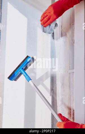 Uomo mani in guanti di gomma lavano le finestre. Faccende domestiche. Disinfezione durante la quarantena a causa di coronavirus. Concetto di pulizia primaverile Foto Stock