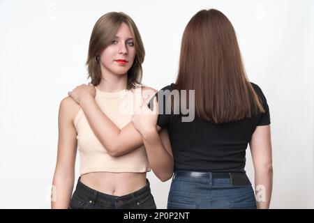 Due generazioni, figlia adolescente e madre adulta che si abbraccia. La figlia di etnia caucasica si trova di fronte e guardando la telecamera Foto Stock