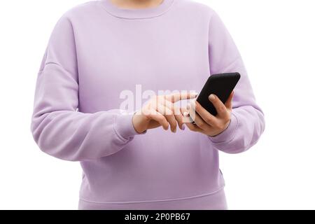 Un tiro corto di una donna in un maglione di lavanda e jeans tiene lo smartphone in mano, puntando, toccando lo schermo. Foto Stock