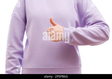 Il colpo corto di una donna in una felpa oversize della lavanda sta mostrando i pollici in su, come segno. Foto Stock