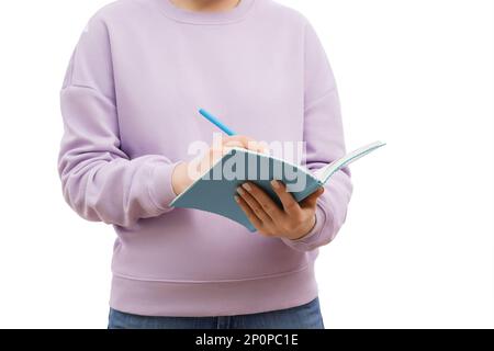 Foto ritagliata di una donna in una felpa oversize in lavanda, con note in un notebook. Foto Stock