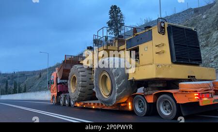 Trasporto della pala gommata di grandi dimensioni al prossimo cantiere minerario, trasporto pesante Foto Stock