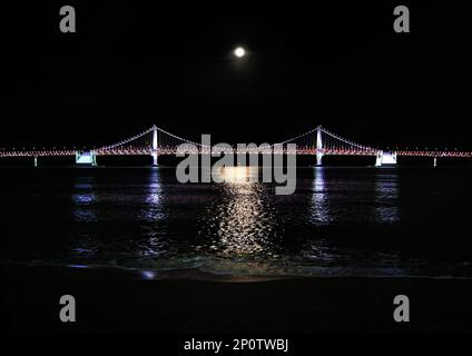 Busan, Corea del Sud - 2019 maggio: Ponte di Busan Gwangan preso dalla spiaggia di Gwangalli di notte con la luna Foto Stock