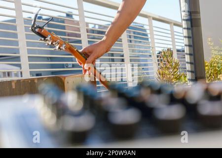 persona irriconoscibile che raccoglie chitarra acustica all'aperto, concetto di musica dal vivo, lezioni di musica e vendita di strumenti, concentrarsi sul background. Foto Stock