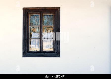 finestra di legno scuro in una parete bianca di vecchio cottage - vista dall'esterno Foto Stock