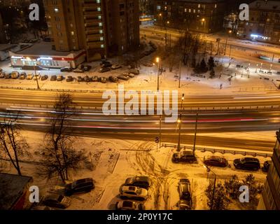 Vista dall'alto della luce proveniente dalle auto che passano sulla strada cittadina nel quartiere residenziale di Mosca nella notte d'inverno Foto Stock