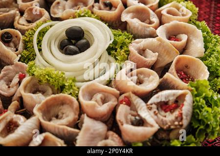 Involtini di aringhe marinate con verdure. Composizione con involtini e verdure marinati di aringhe. Cibo sano Foto Stock