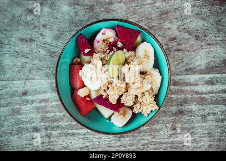 Ciotola sana con avena, frutta a fette: Banana, frutto del drago, lime, papaia. Foto del cibo dall'alto. Foto Stock