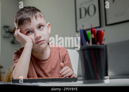 Il ragazzo seduto al tavolo, studiava matematica, si stanca e si appoggiò in mano Foto Stock