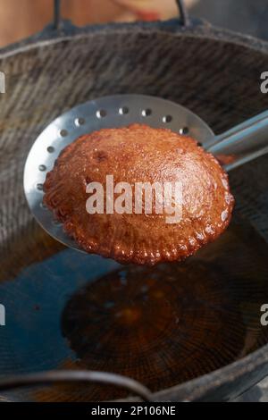 vista ravvicinata del dolce fritto dello sri lanka chiamato kevum o kavum su un cucchiaio per friggere, dessert tradizionale a base di farina di riso e zucchero di palma Foto Stock