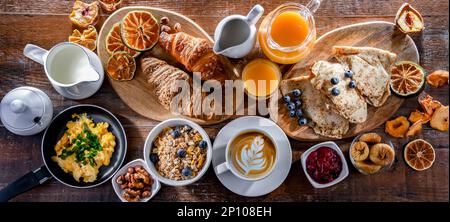 La colazione è servita con caffè, succo d'arancia, uova strapazzate, cereali, pancake e croissant. Foto Stock