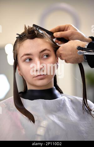 il parrucchiere maschile sta pettinando i capelli della cliente femminile. Foto Stock