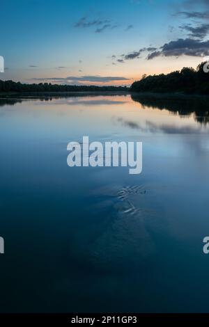 Massi subacquei nel fiume al crepuscolo, paesaggio del fiume Sava con silhouette foresta sulla riva e nuvole che si riflettono in acqua Foto Stock