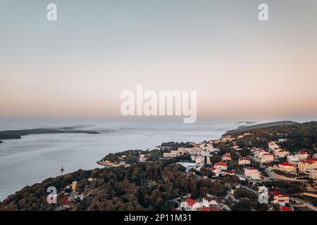 La ripresa aerea cattura la bellezza della costa di Hvar all'alba di una mattina d'estate. Le acque cristalline e le aspre scogliere sono illuminate dal Foto Stock