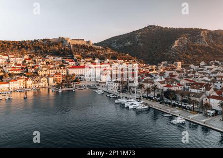 La ripresa aerea cattura la bellezza della costa di Hvar all'alba di una mattina d'estate. Le acque cristalline e le aspre scogliere sono illuminate dal Foto Stock