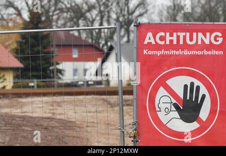03 marzo 2023, Brandeburgo, Oranienburg: Un cartello "attenzione lavoro di smaltimento delle ordigni esplosive" è pubblicato vicino al sito dove è stata trovata una bomba della seconda guerra mondiale di fronte agli edifici residenziali durante una riunione in loco del Comitato interno del Parlamento dello Stato di Brandeburgo. Su invito della città, i membri del Comitato interno hanno visitato il sito di una bomba trovare sulla strada per la fattoria Bieber sul fiume Havel. Lì, una bomba della seconda guerra mondiale sarà disinnescata dietro un muro di contenitori a due piani il 22 marzo 2023. Foto: Soeren Stache/dpa Foto Stock