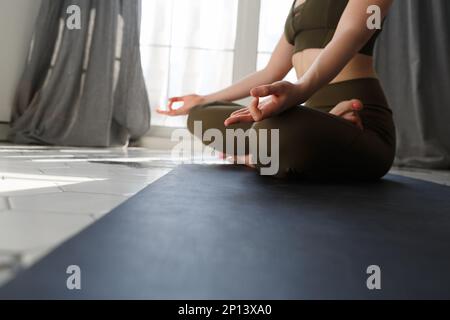 Giovane donna medita dopo lo yoga a casa. Primo piano foto di una ragazza yoga seduta in posa lotus e fare meditazione Foto Stock