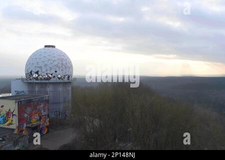 Berlino, Germania. 03rd Mar, 2023. Visto dal Teufelsberg di Berlino, il sole tramonta dietro l'orizzonte sotto i cieli e le temperature fredde. Sulla montagna sono gli edifici prominenti di una stazione di controllo e ascolto del traffico aereo i cui edifici sono vuoti e fatiscenti e sono attualmente utilizzati artisticamente. Credit: Felix Hörhager/dpa/Alamy Live News Foto Stock