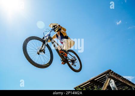 Green Glade; Russia - 16 luglio; 2022: Atleta femminile salto gap su una mountain bike con pneumatici Maxxis in Ural Downhill Cup Foto Stock