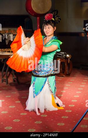 Il ballerino dei fan esegue una divertente danza durante una rappresentazione di musica tradizionale cinese nell'auditorium all'interno del Campanile nella città cinese di Xian. RPC, Cina. L'icona e il punto di riferimento dell'edificio, risalente a 600 anni fa, è popolare tra i turisti che guardano e ascoltano eventi di dimostrazione musicale e spettacoli musicali suonati con strumenti tradizionali cinesi. (125) Foto Stock