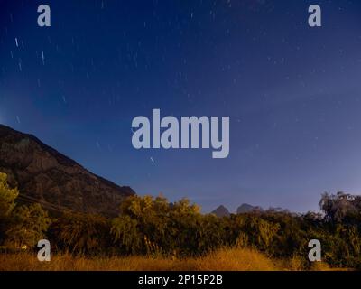Tracce di stelle che si muovono nel cielo notturno sulle montagne di Beldibi, Turchia, Panorama di cielo stellato su campi e colline nella notte limpida. Foto Stock