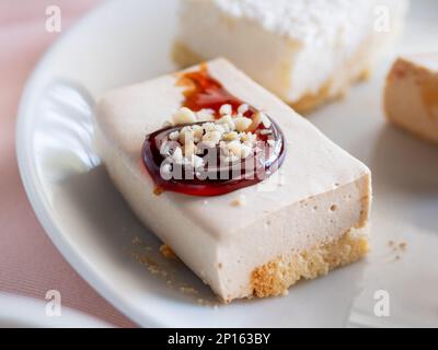 Piatto bianco pieno di dolci diversi. Gustosi dessert con farcitura, fiocchi di cocco. Foto Stock