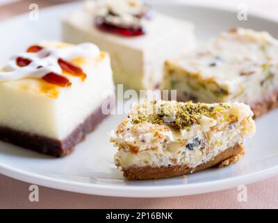 Piatto bianco pieno di dolci diversi. Gustosi dessert con farcitura, pistacchi. Foto Stock