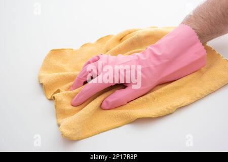 Guanto per la pulizia in lattice rosa su mano maschio caucasica con un panno in microfibra giallo che rende isolato il gesto di pulizia su sfondo bianco. Foto Stock