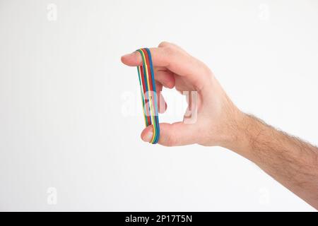 Fasce di gomma colorate multiple tese intorno alle dita della mano maschio caucasiche isolate sul bianco. Foto Stock