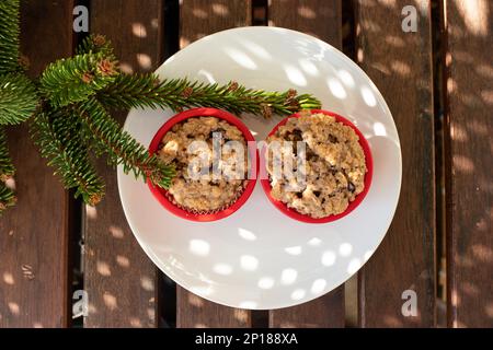 Due muffin ai mirtilli su un piatto bianco all'esterno per una vista fresca dall'alto. Foto Stock